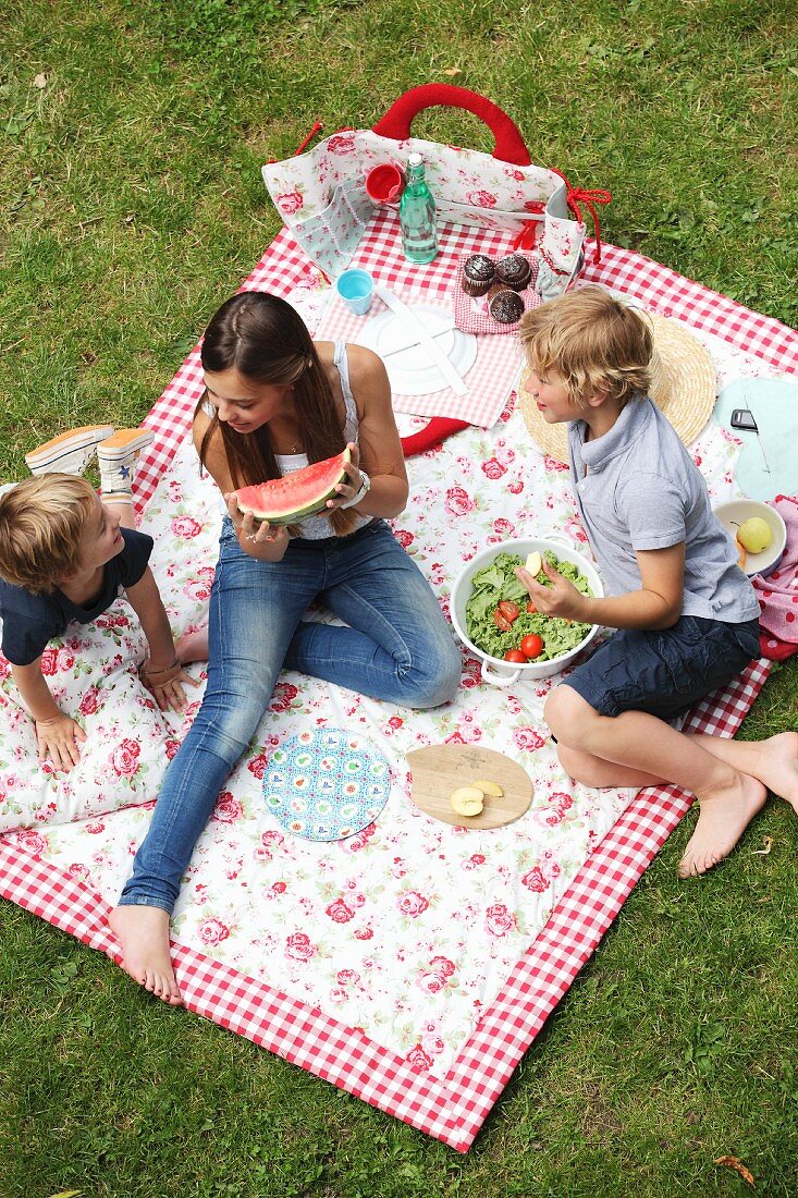 Kinder auf geblümter Picknickdecke beim Essen