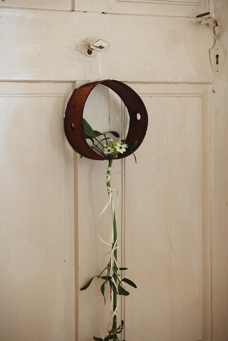 Rusty metal ring with delicate, elegant arrangement of Star-of-Bethlehem on white wooden door