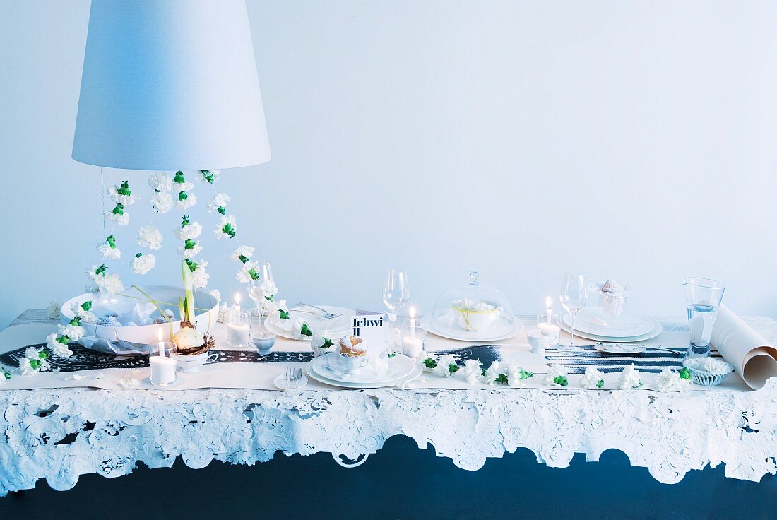 Festliche Hochzeitstafel mit weisser Nelkengirlande und Kerzenlicht, darüber teilweise sichtbare Hängeleuchte mit weißem Schirm