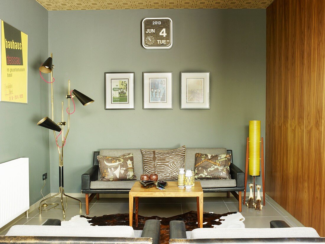 Loungeecke mit grau getönten Wänden in modernem Retrolook mit kleinem Couchtisch, Tierfellteppich & Sofa zwischen Stehleuchten im Fiftiesstil