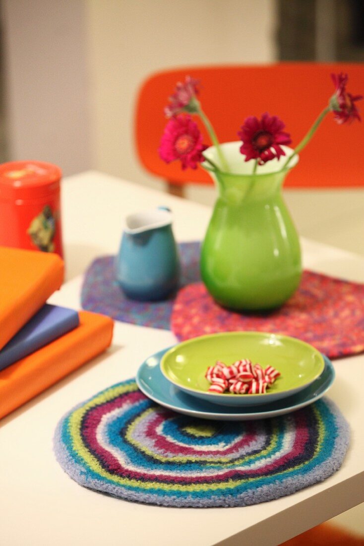 Colourful table arrangement with plates and vase on felt coasters