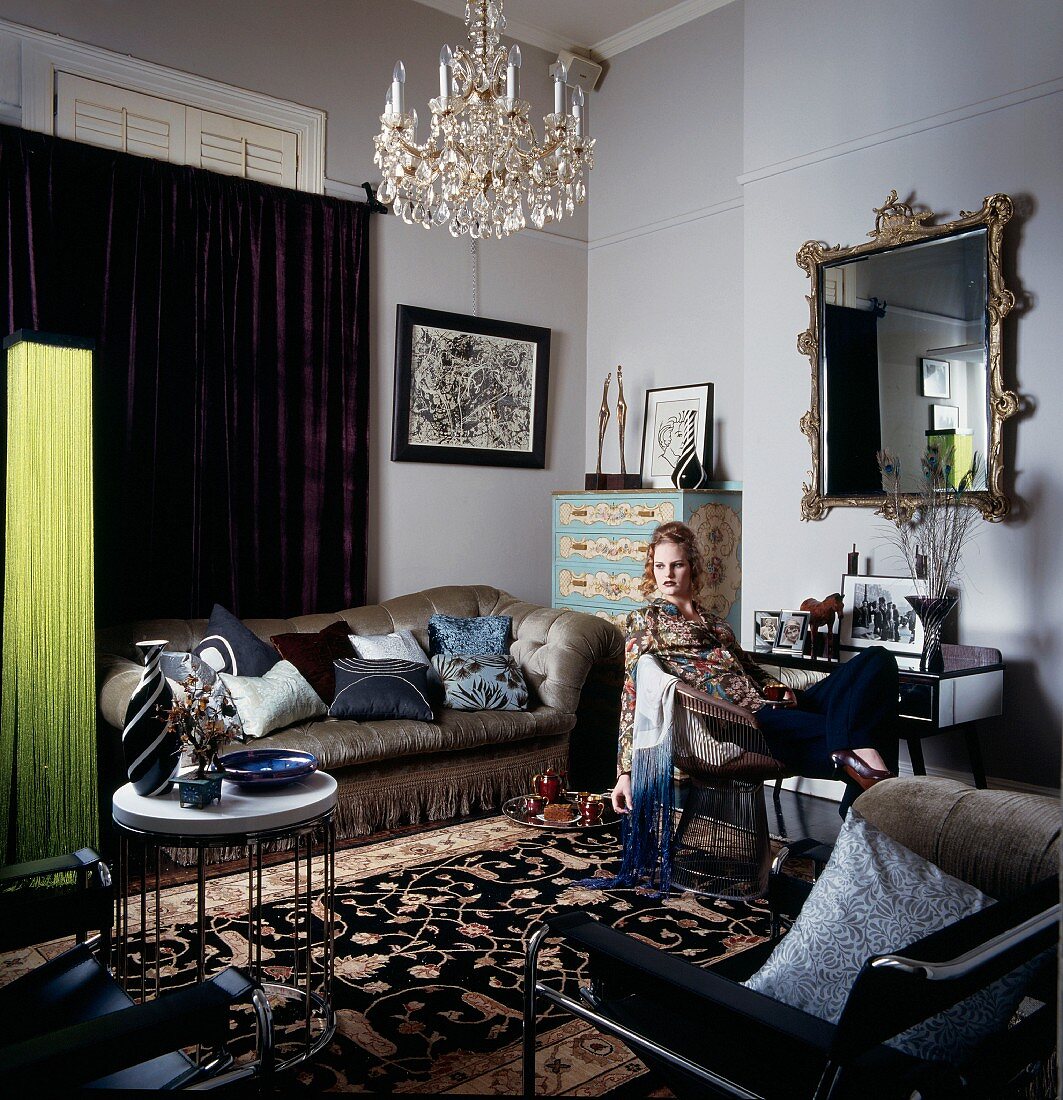 Wohnzimmer mit Samtsofa, Wandspiegel und chinesischem Seidenteppich; Frau sitzt im Armlehnstuhl