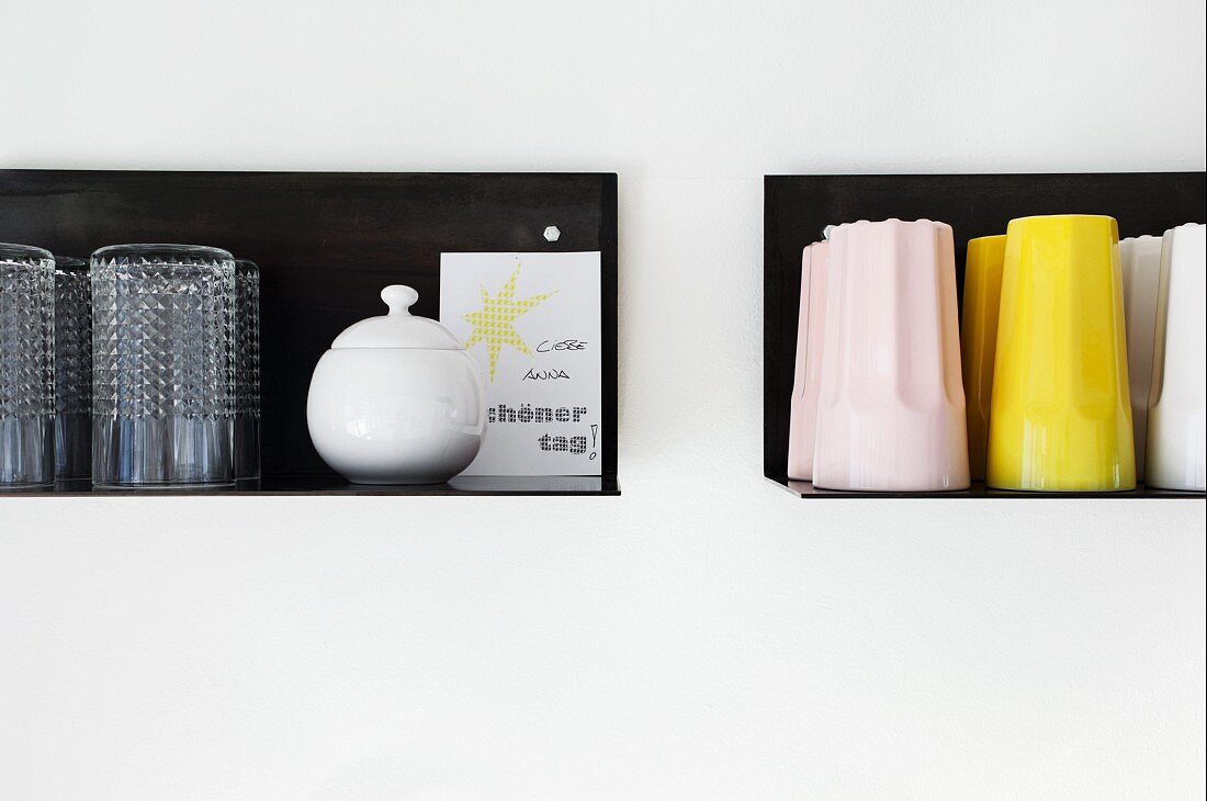 Glasses and colourful beakers on black, metal floating shelves