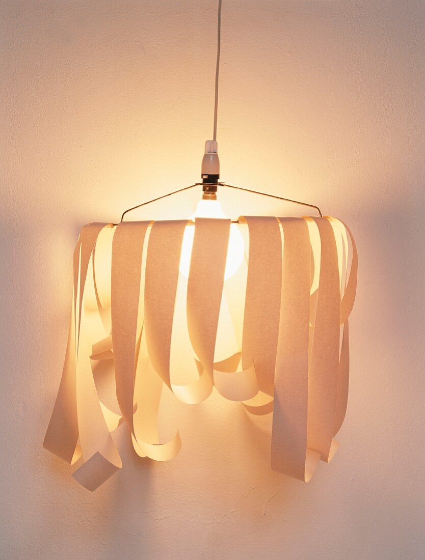 Hand-crafted sconce lamp with strips of paper attached to wire frame