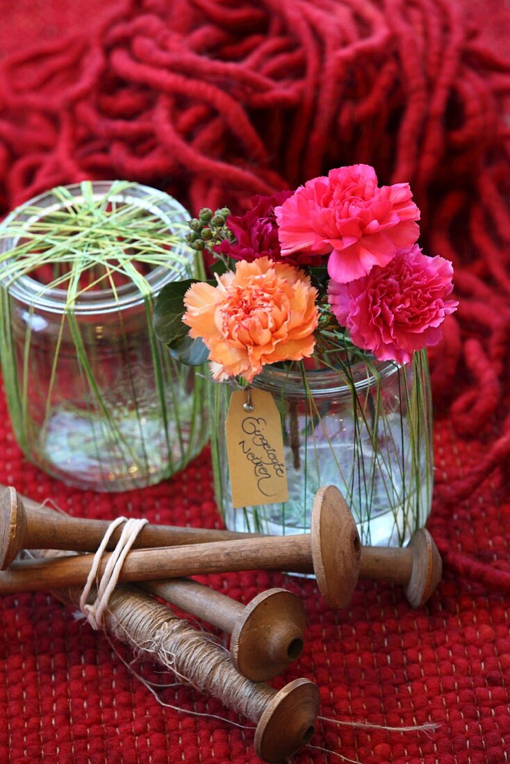 Pinks in preserving jar wrapped in green yarn and wooden spindles
