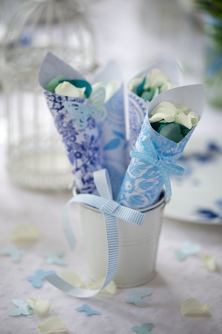 Blau-weiss gemusterte Papiertüten mit Blütenblättern für eine Hochzeit