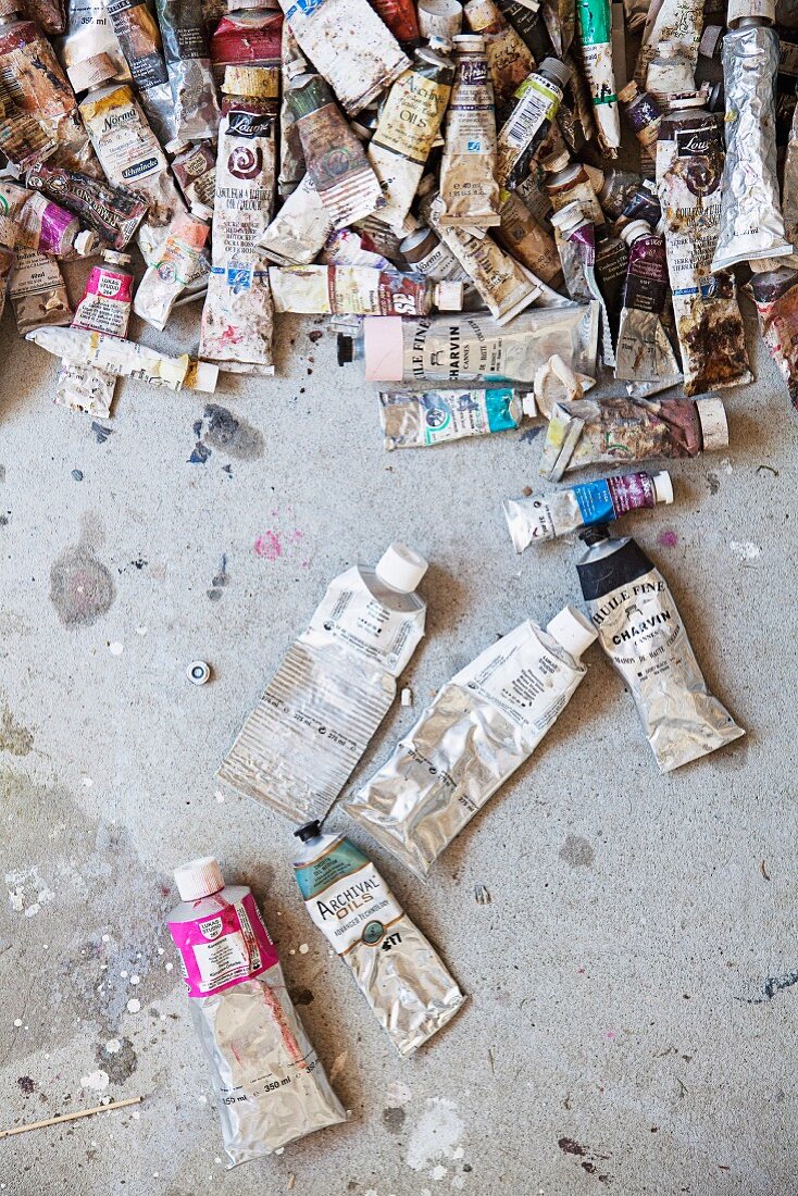 Many used tubes of paint on concrete floor