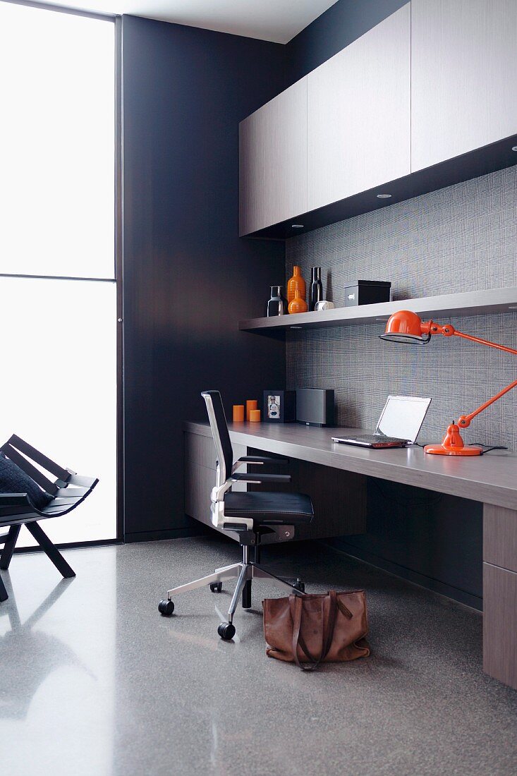 Designer work area with fitted desk, office chair, orange designer desk lamp and floor-to-ceiling window