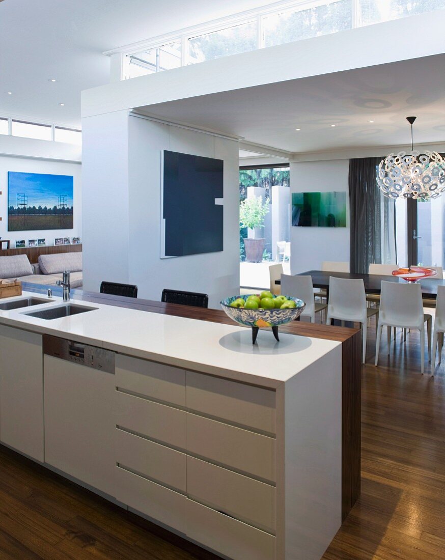 Blick von Küchentheke mit Frühstücksbar auf den offenen Wohnraum mit höhenversetzten Zonierungen