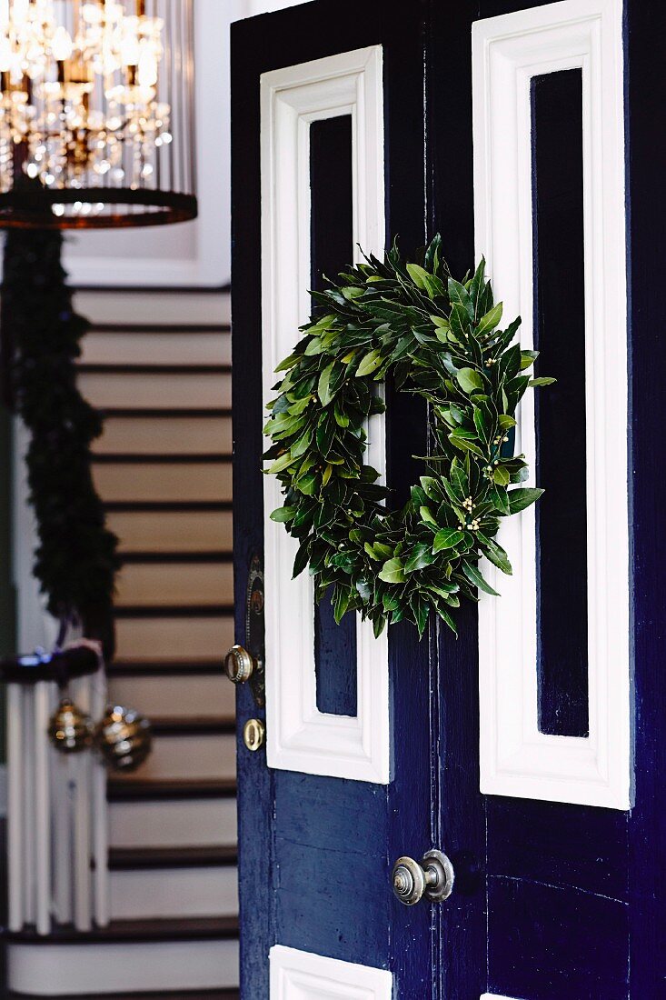 Geöffnete blau-weiße Hauseingangstür dekoriert mit weihnachtlichem Türkranz