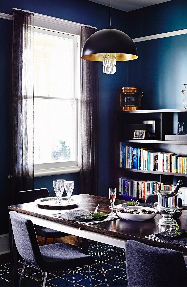 Esszimmer in Blau- & Grautönen mit gedecktem Tisch & Bücherregal