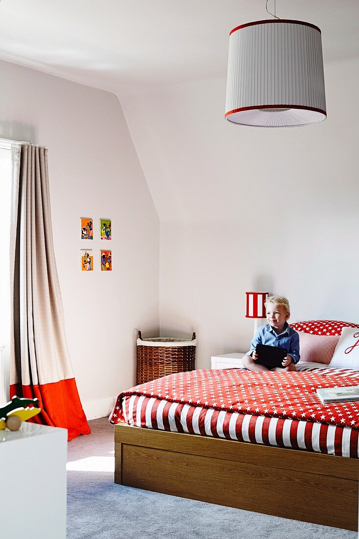 Large bed with red and white bed linen in child's bedroom