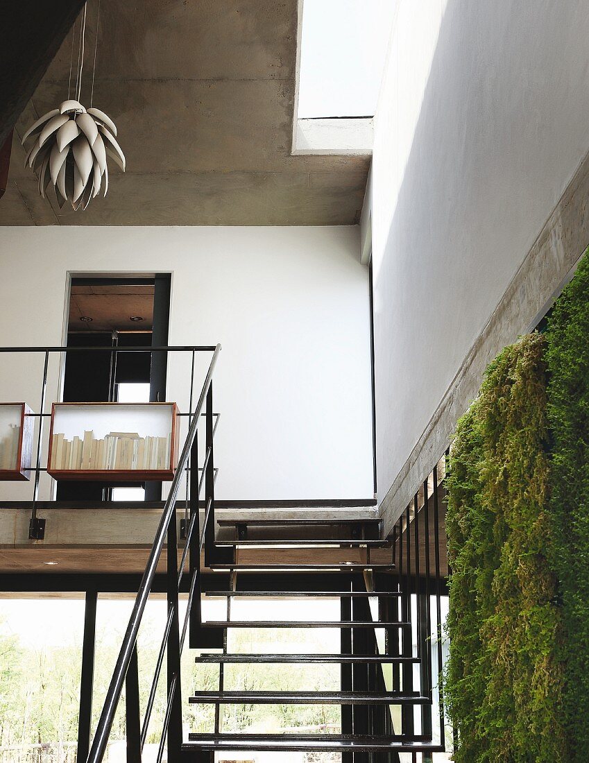 Wohnraumtreppe aus Schwarzstahl und Galeriegang mit Naturdesign Hängeleuchte; mit Regenwasser gespeiste Vegetationswand im Vordergrund