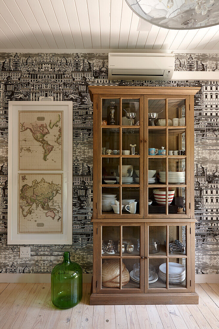 Crockery cupboard and world maps in front of wall with designer wallpaper