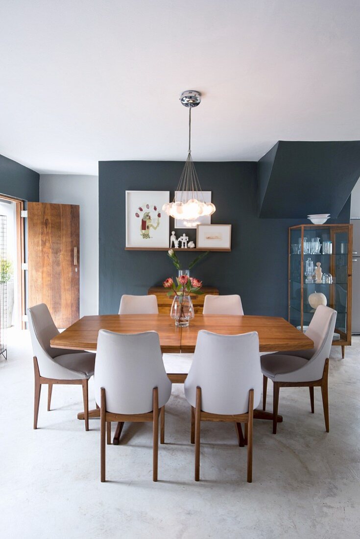 Chairs with white upholstery and wooden table in dining area with concrete floor