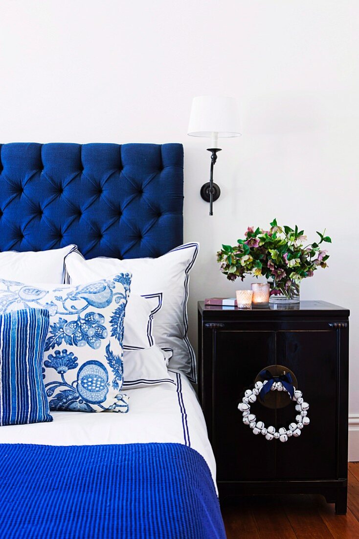 Bed with blue headboard & blue and white bed linen and scatter cushions