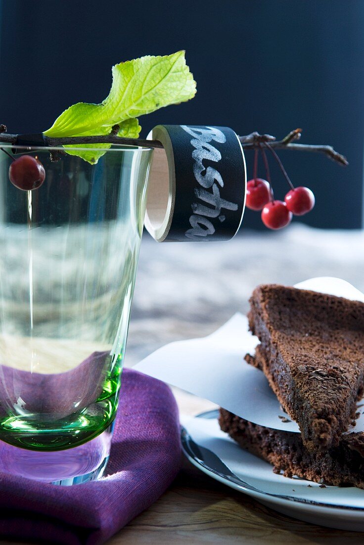 Two slices of chocolate cake and water glass with labelled napkin ring on cherry twig