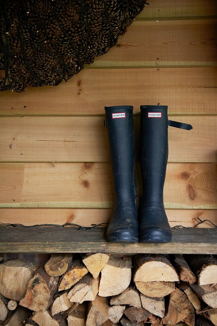Pair of boots on board shelf above stacked firewood