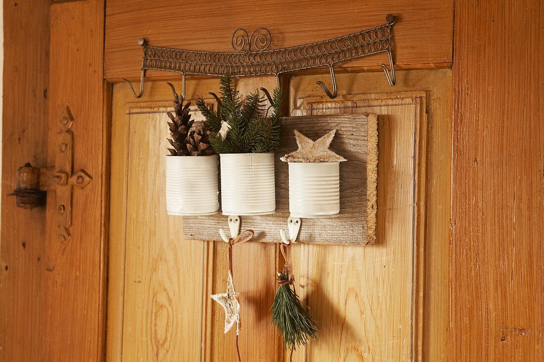 White tin cans with Christmas decorations hung on wooden interior door