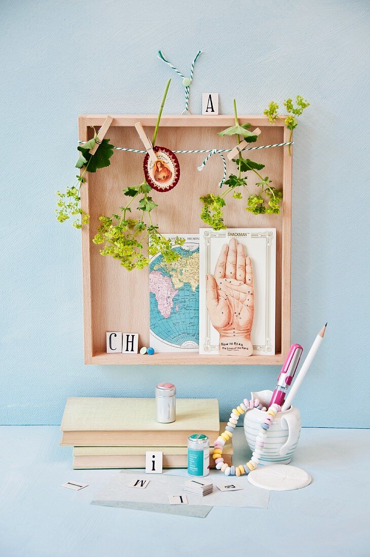 Lady's mantle flowers hung up to dry in wooden box with cards on wall above desk