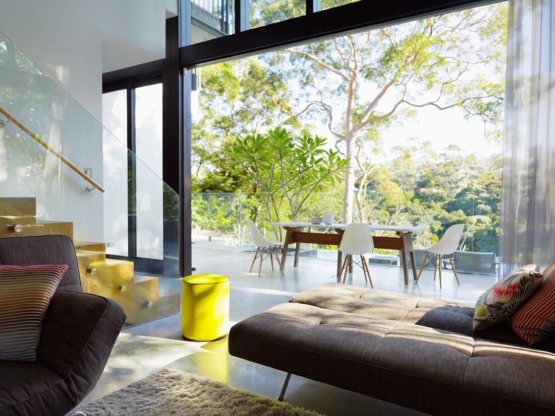 Blick von Wohnraum durch die offene Glasschiebefront auf Balkon mit Eames Stühlen