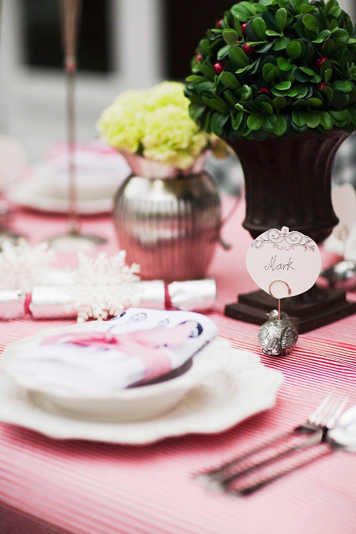 Festlich gedeckter Tisch mit Blumendeko, Tischkärtchenhalter an kleinem Metallvogel und rot-weiss gestreifte Decke