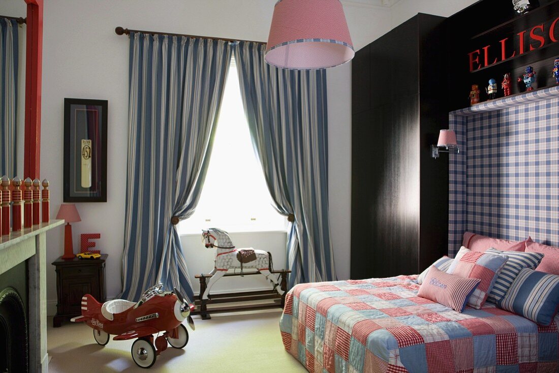 Propellermaschine als Dreirad in Jungenzimmer mit antikisierenden Elementen; dunkler Einbauschrank mit der integrierten Rückwand eines Doppelbetts mit Patchworkdecke