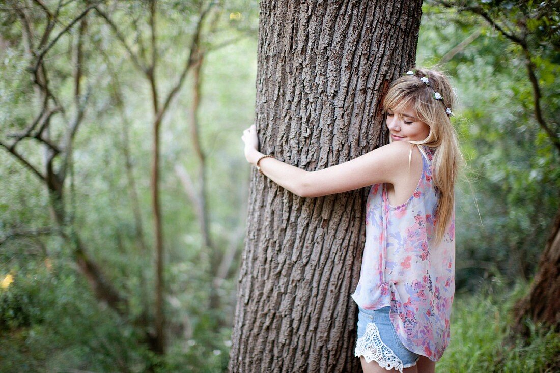 Teenage girl hugging tree in woods
