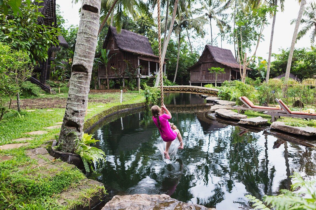 Mädchen schwingt auf Seil im Garten (Ubud, Bali, Indonesien)