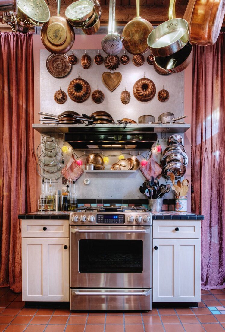 Küchenzeile mit Edelstahlherd, aufgehängten Töpfen, Pfannen und alten Napfkuchenformen