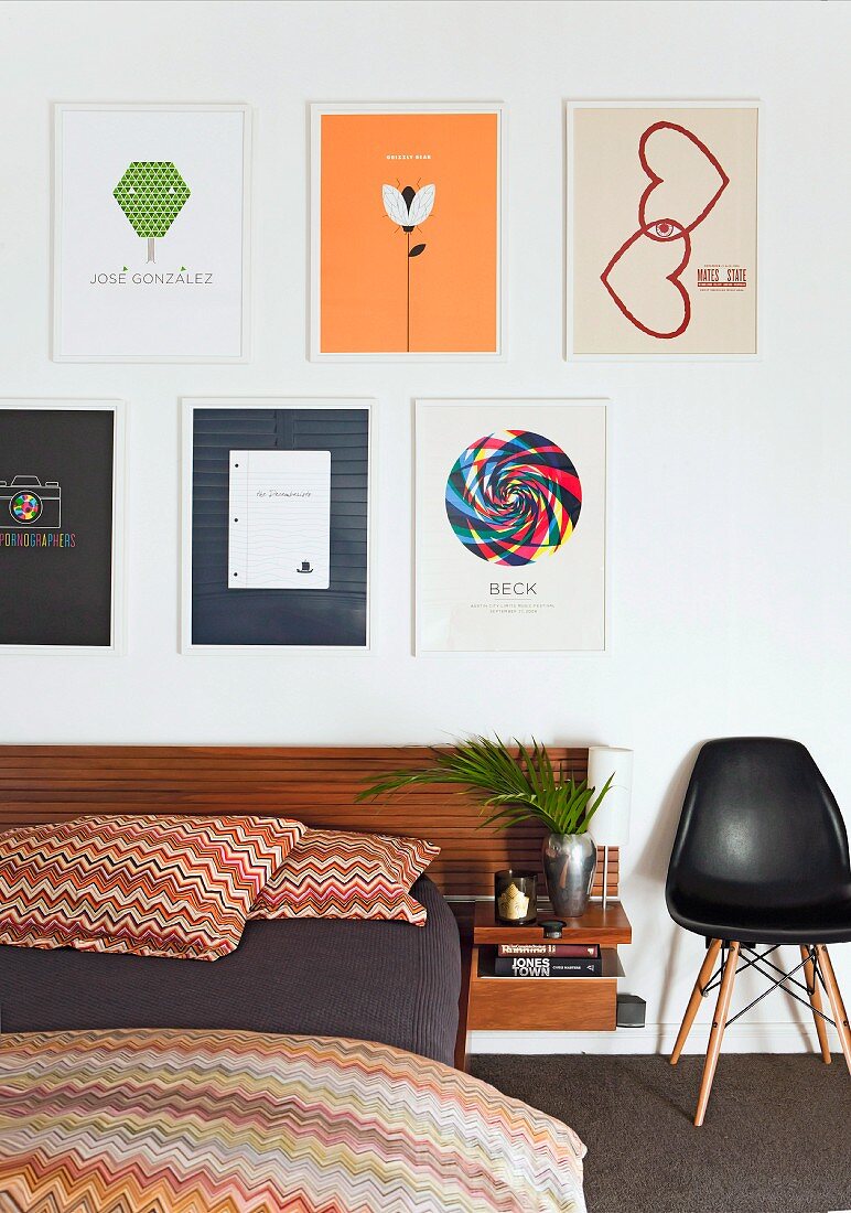 Modernes Bett mit Missoni-Bettwäsche und klassischem Schalenstuhl an Wand unter gerahmten Bildern