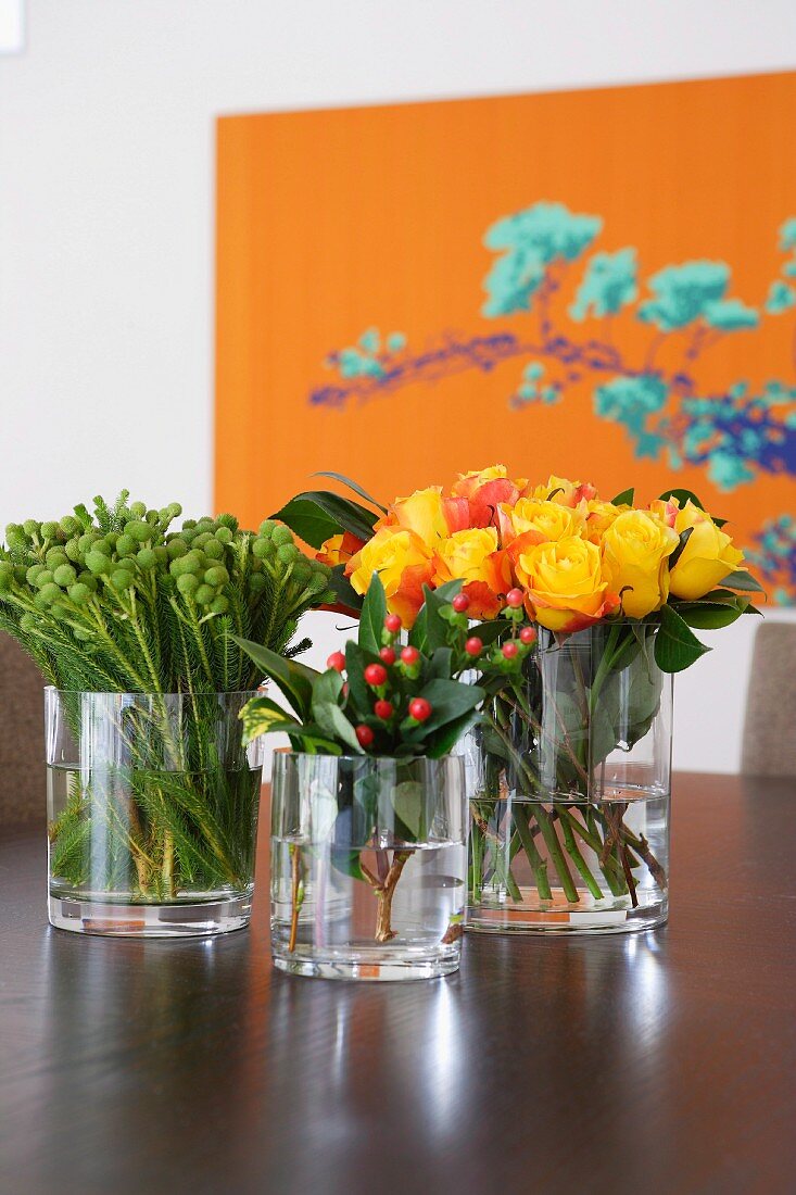 Bouquets in glass vases on table; large floral artwork in background