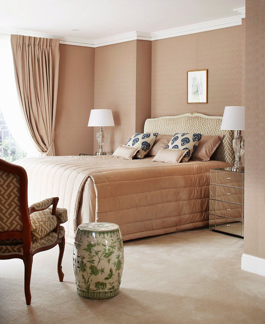 Classic, elegant bedroom in pale beige with antique-style furniture and ceramic stool