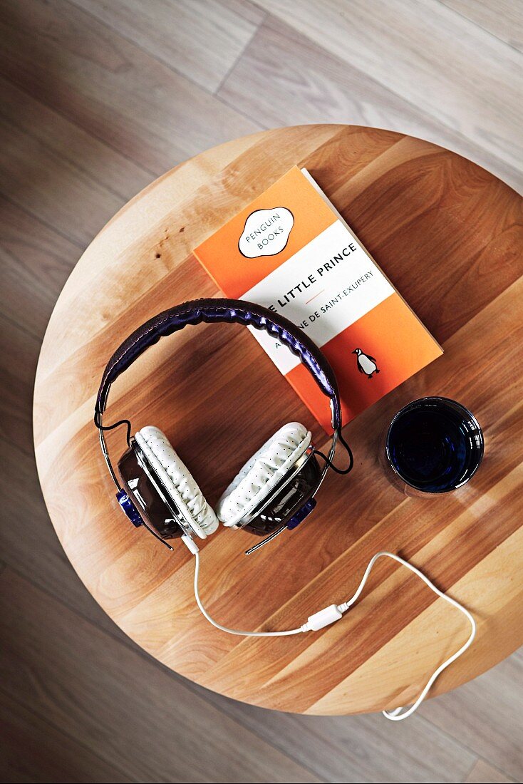 Headphones, beaker and book on wooden stool (top view)
