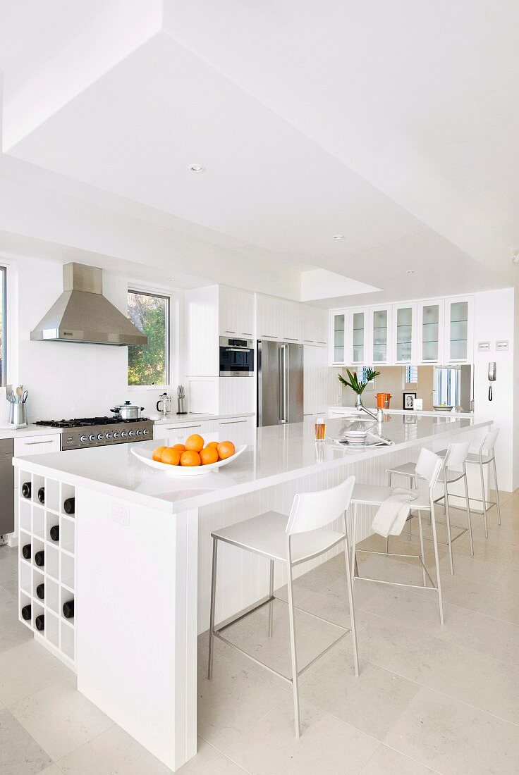 White glossy counter and designer bar stools in open-plan kitchen