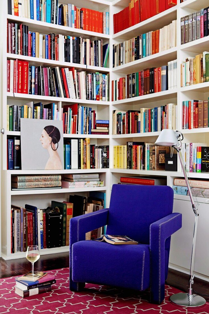 Königsblauer Sessel und Stehlampe vor Bücherregal