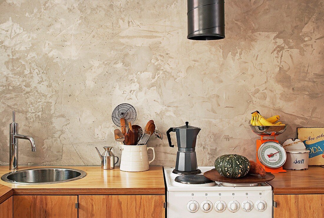 Küchenzeile mit Holzfront und Retro Elektroherd vor Wand mit rustikaler Spachteltechnik