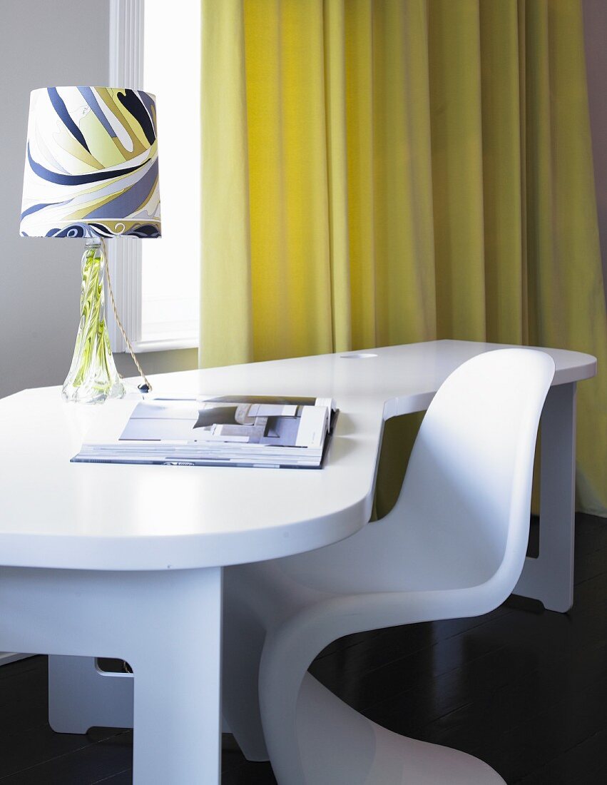Weisser Schreibtisch mit gemusterter Lampe und Designerstuhl