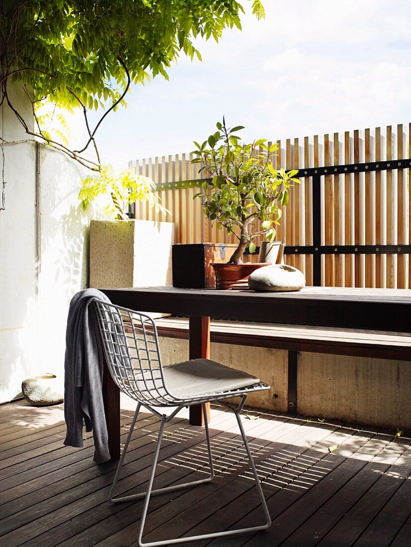 Bauhausstuhl und Tisch auf sonnenbeschienener Holzterrasse mit Zaun