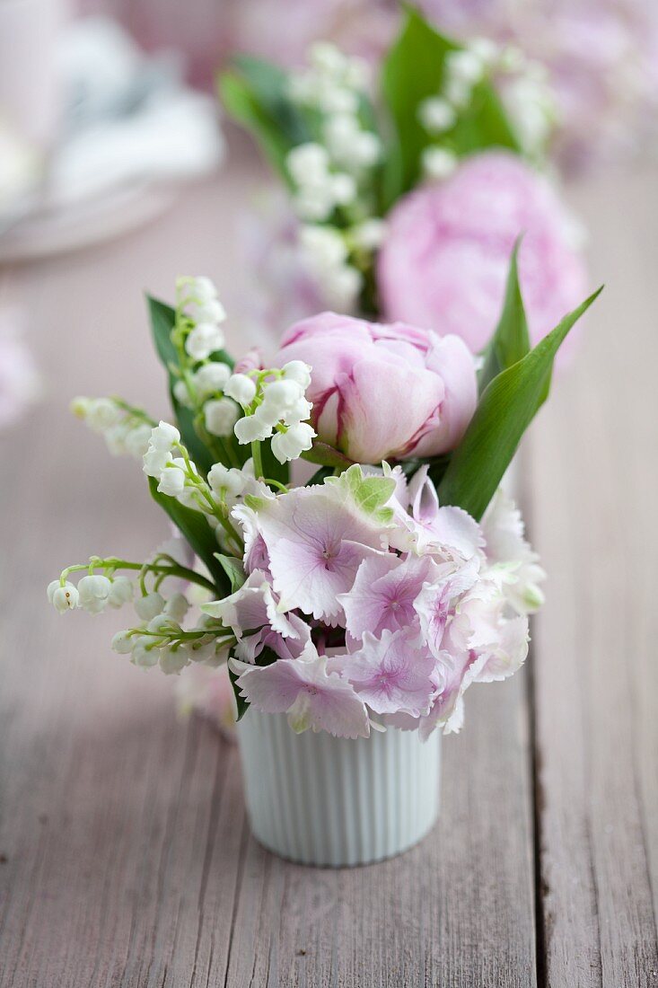 Posies of hydrangeas, lily-off-the-valley and peonies in white ramekins