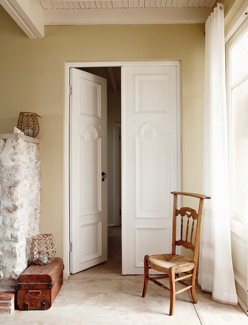 Antique wooden chair in front of double doors in rustic foyer