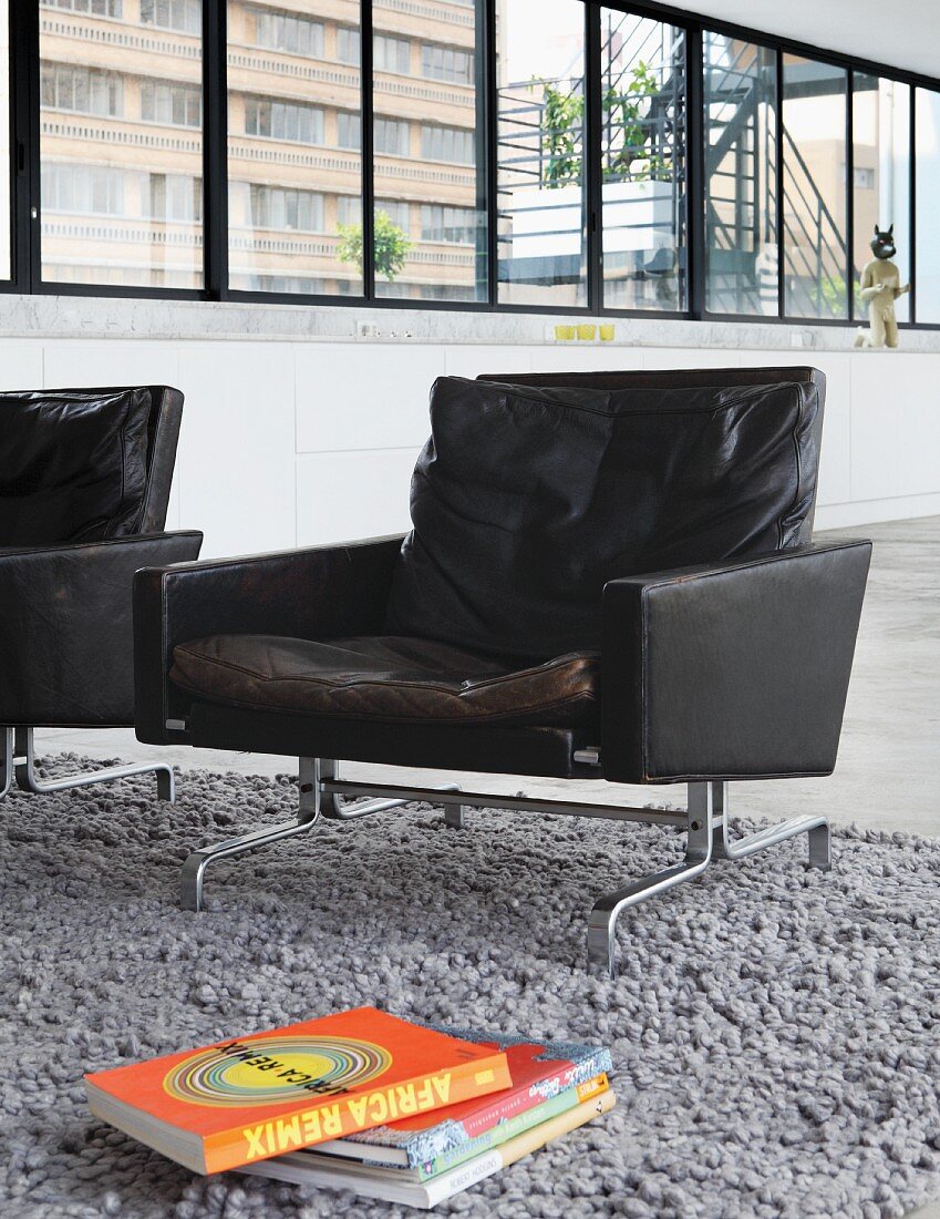 Schwarzer Retro-Ledersessel auf grauem Hochflorteppich in Designer-Loftwohnung