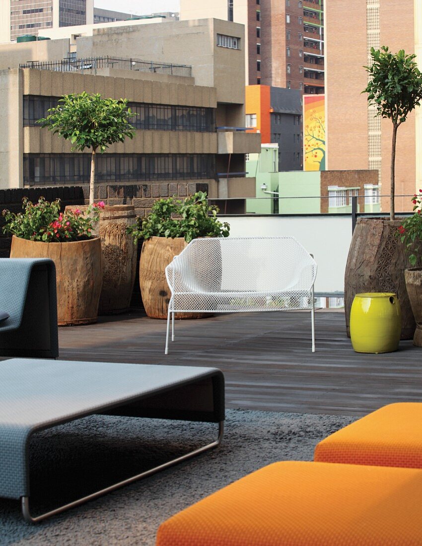 Sitzbereiche mit Designermöbeln und Pflanztöpfen in ausgehöhlten Baumstämmen auf Loftterrasse in Johannesburger City