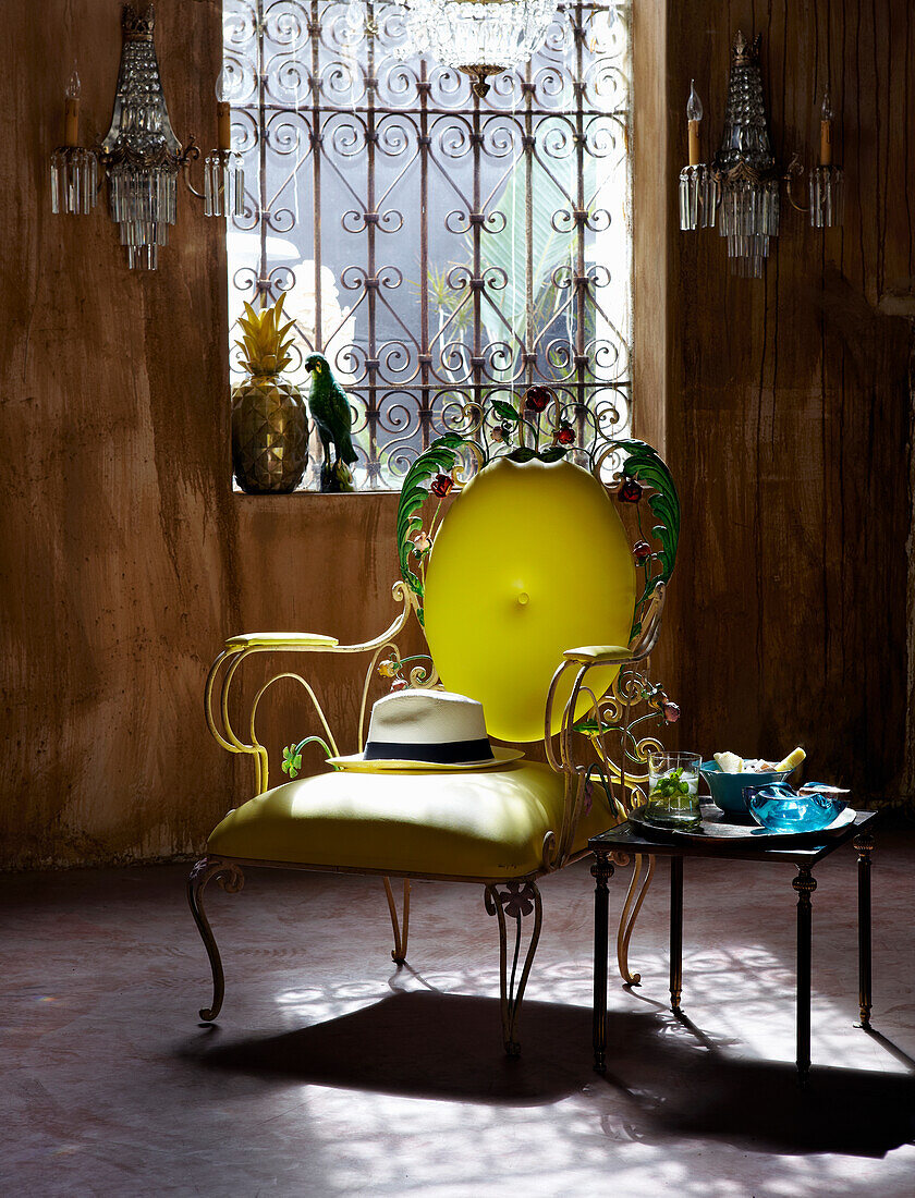 Gelber Stuhl mit Panamahut und Beistelltisch im Zimmer mit Holzverkleidung