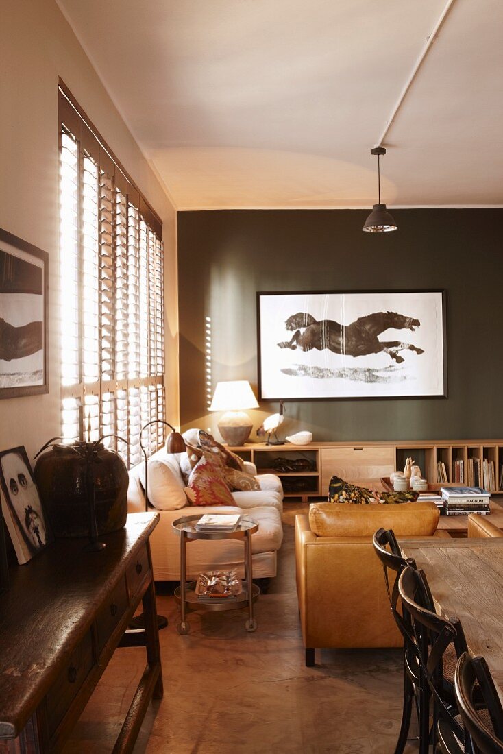 Artistic picture of horse on dark grey wall in lounge area with wooden and upholstered furniture and vintage atmosphere