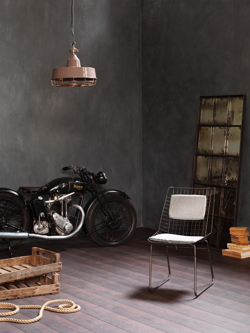 Zimmerecke mit Vintage Motorrad, Metallgitterstuhl und rustikalen Holzkisten