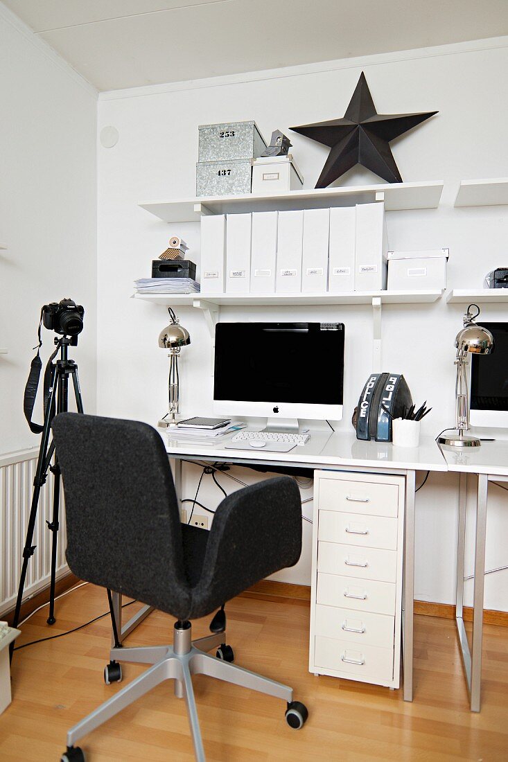 Weisses Home Office mit dunkelgrauem Drehstuhl, Kamera auf Stativ und schwarzem Deko Stern