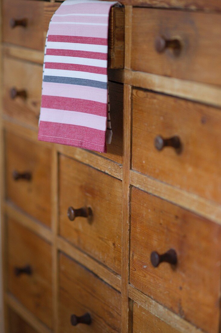 Tea towel hanging out of slightly open drawer of rustic chest of drawers