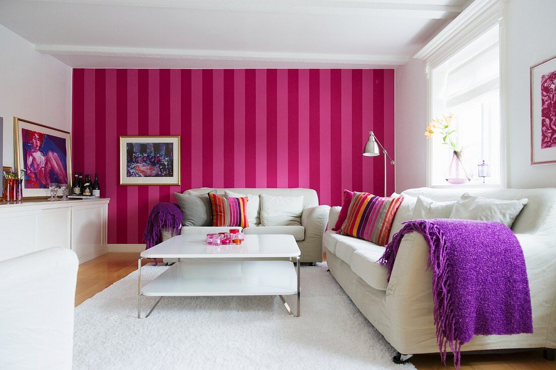 Skandinavisches Wohnzimmer mit weissen Möbeln und rot-pink gestreifter Tapete