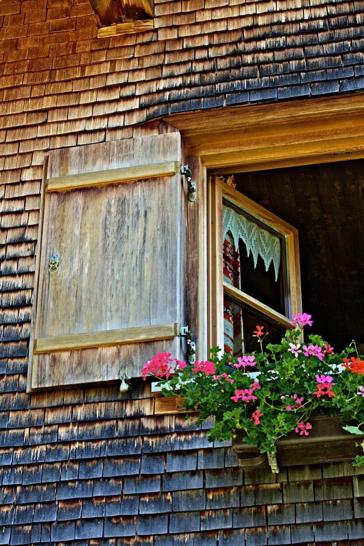 Fenster mit Blumenschmuck von altem Bauernhof (Bregenzerwald, Vorarlberg, Österreich)
